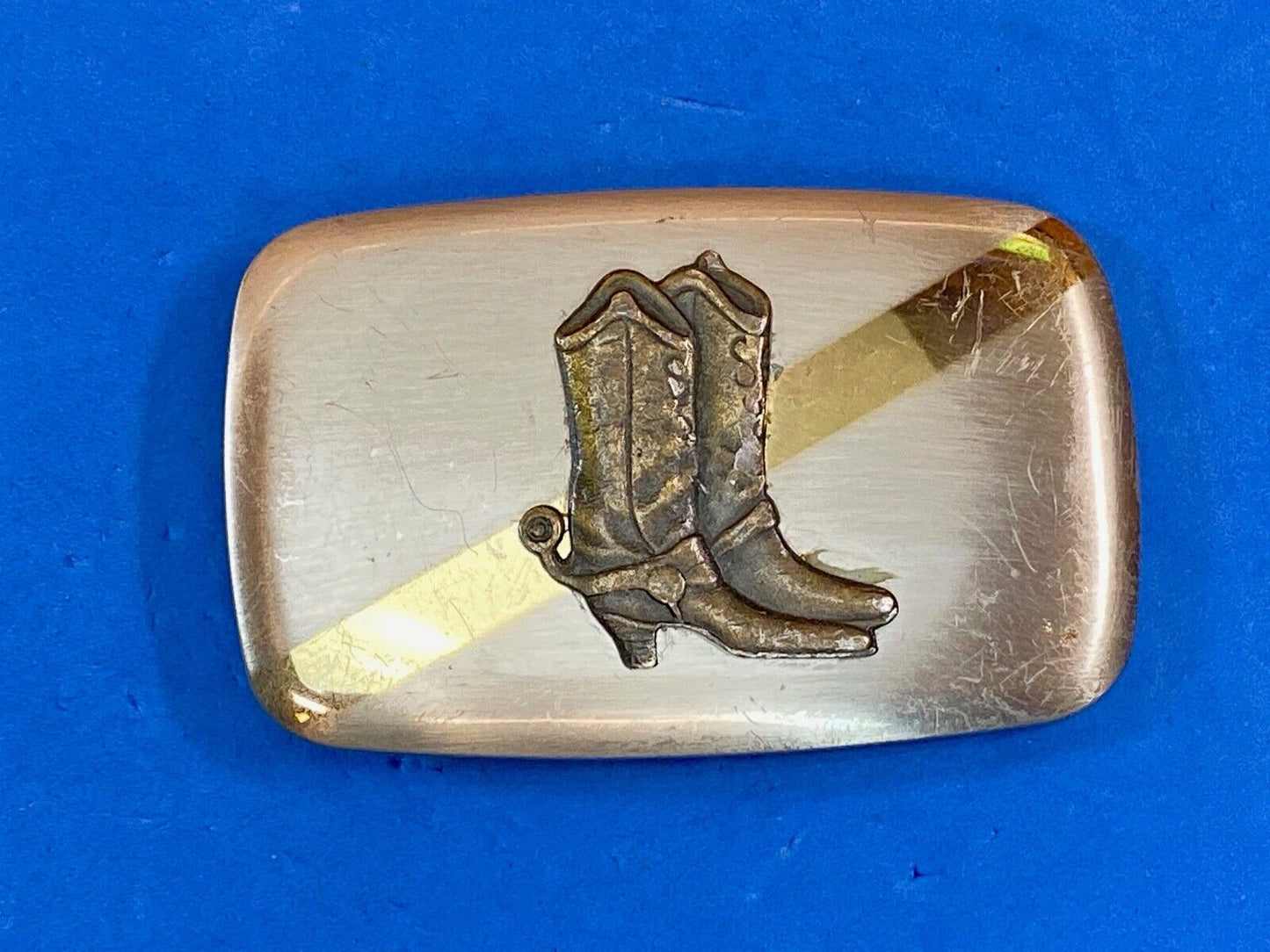 Vintage cowboy boots with spurs in center of mixed metal western belt buckle