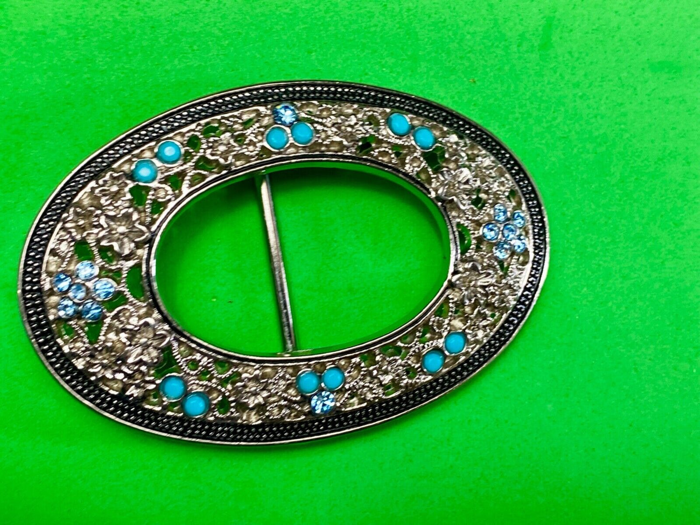Unique blue rhinestone accented oval see though silver tone belt buckle