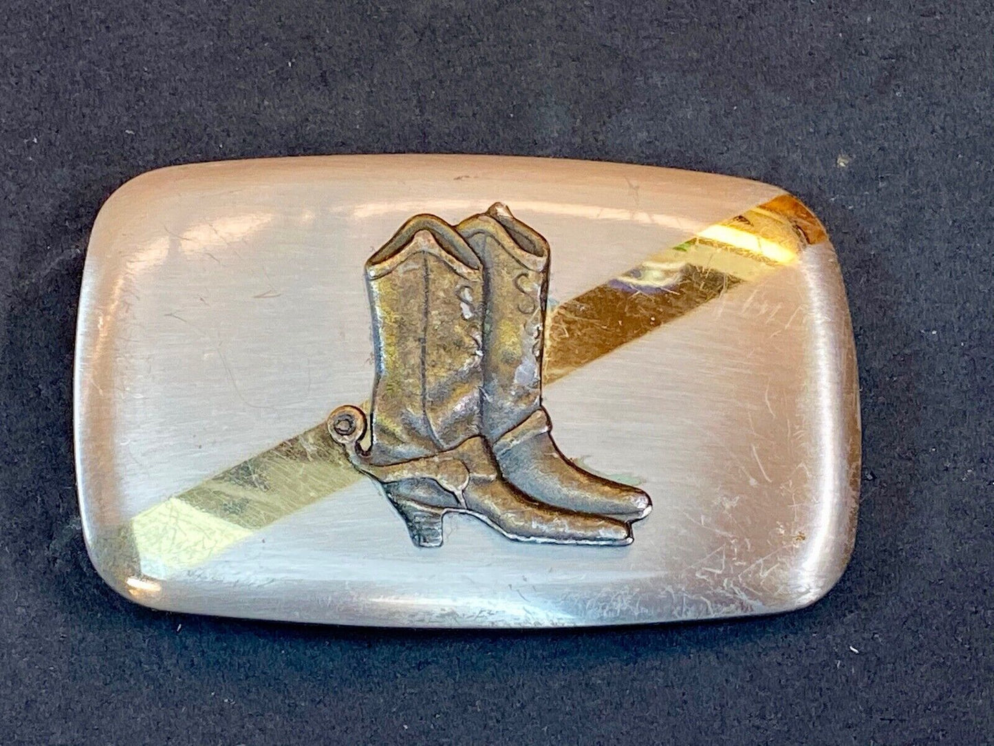 Vintage cowboy boots with spurs in center of mixed metal western belt buckle
