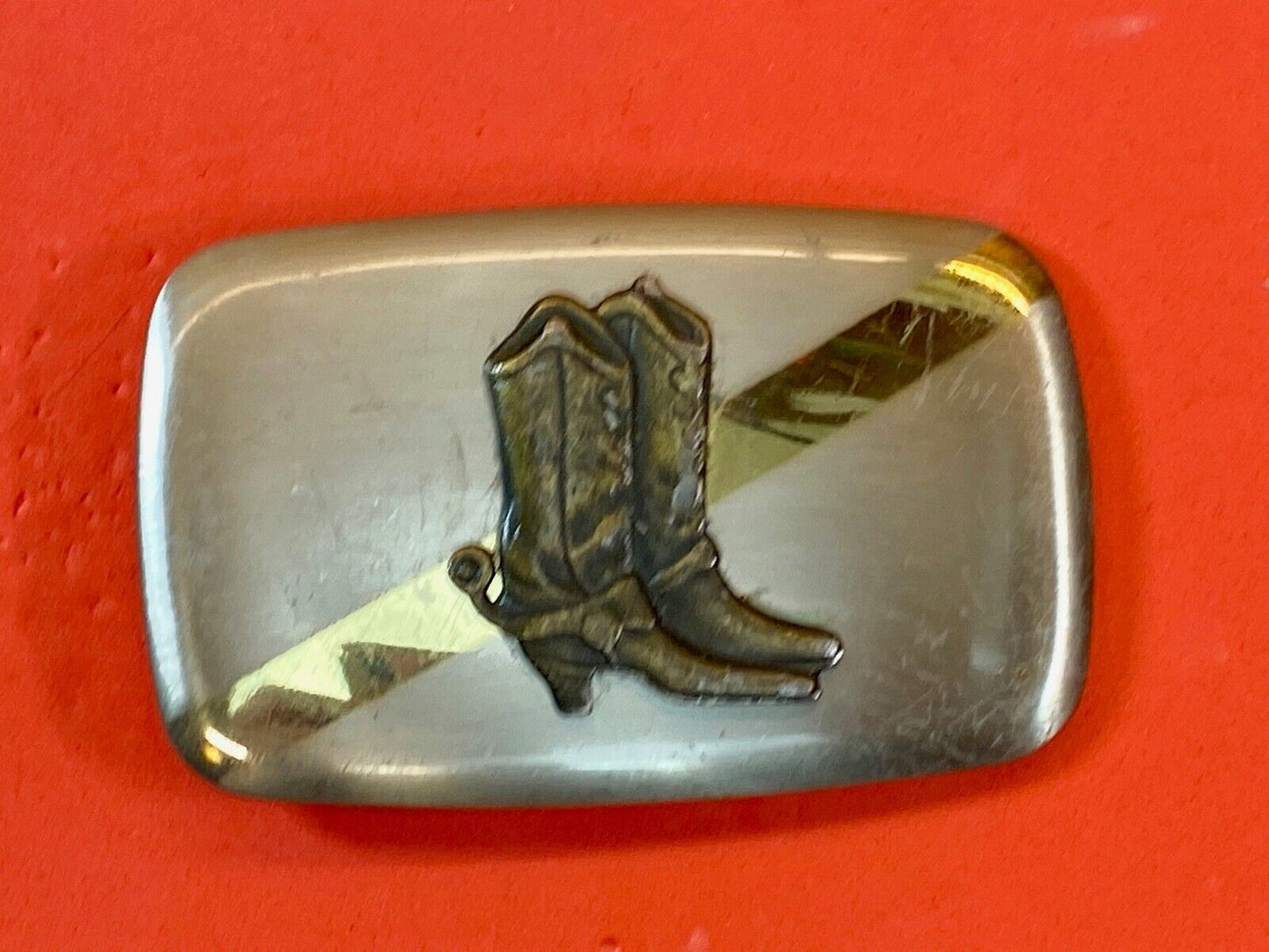 Vintage cowboy boots with spurs in center of mixed metal western belt buckle