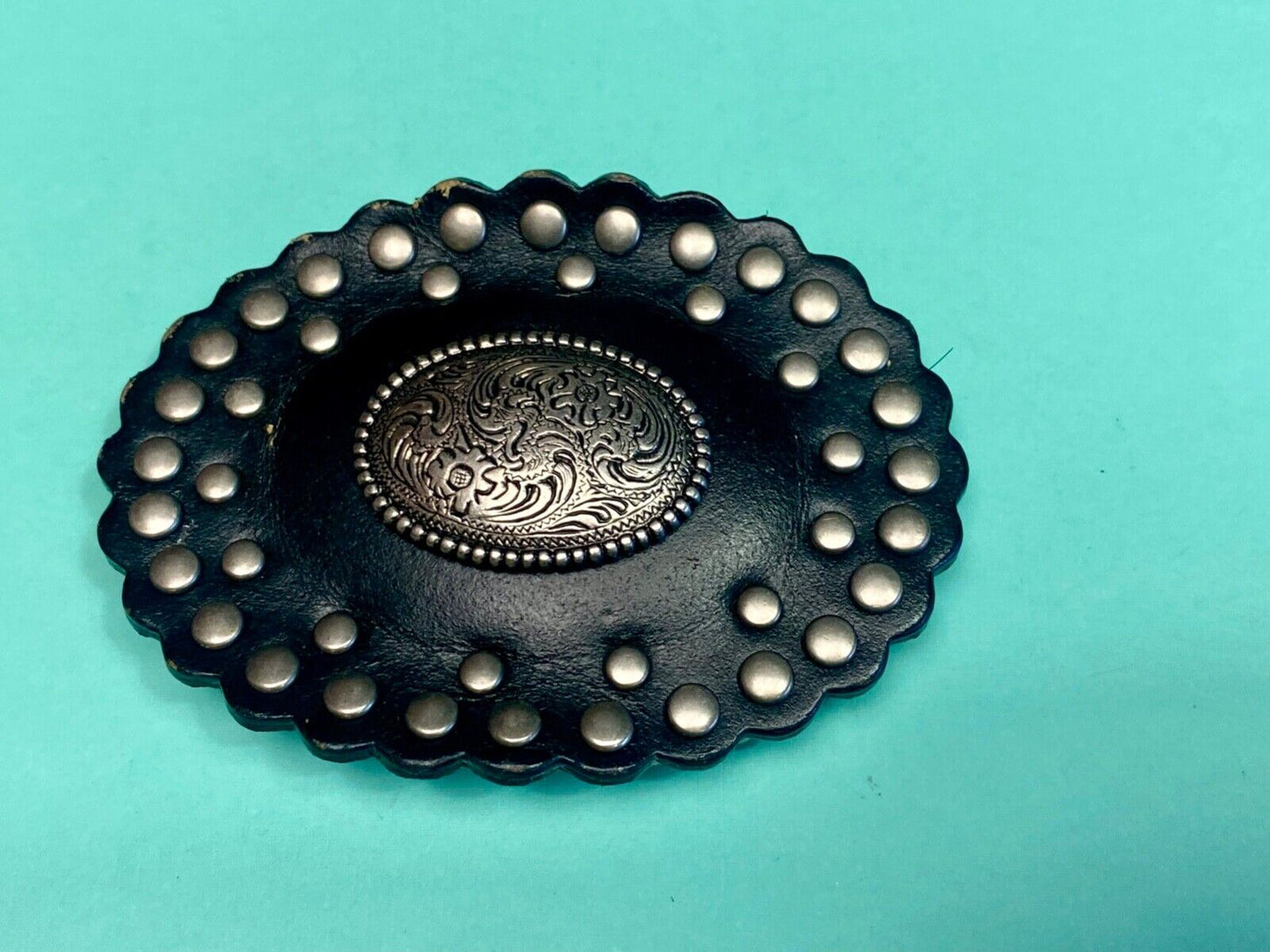 4" wide studded black leather oval belt buckle with flower swirl center