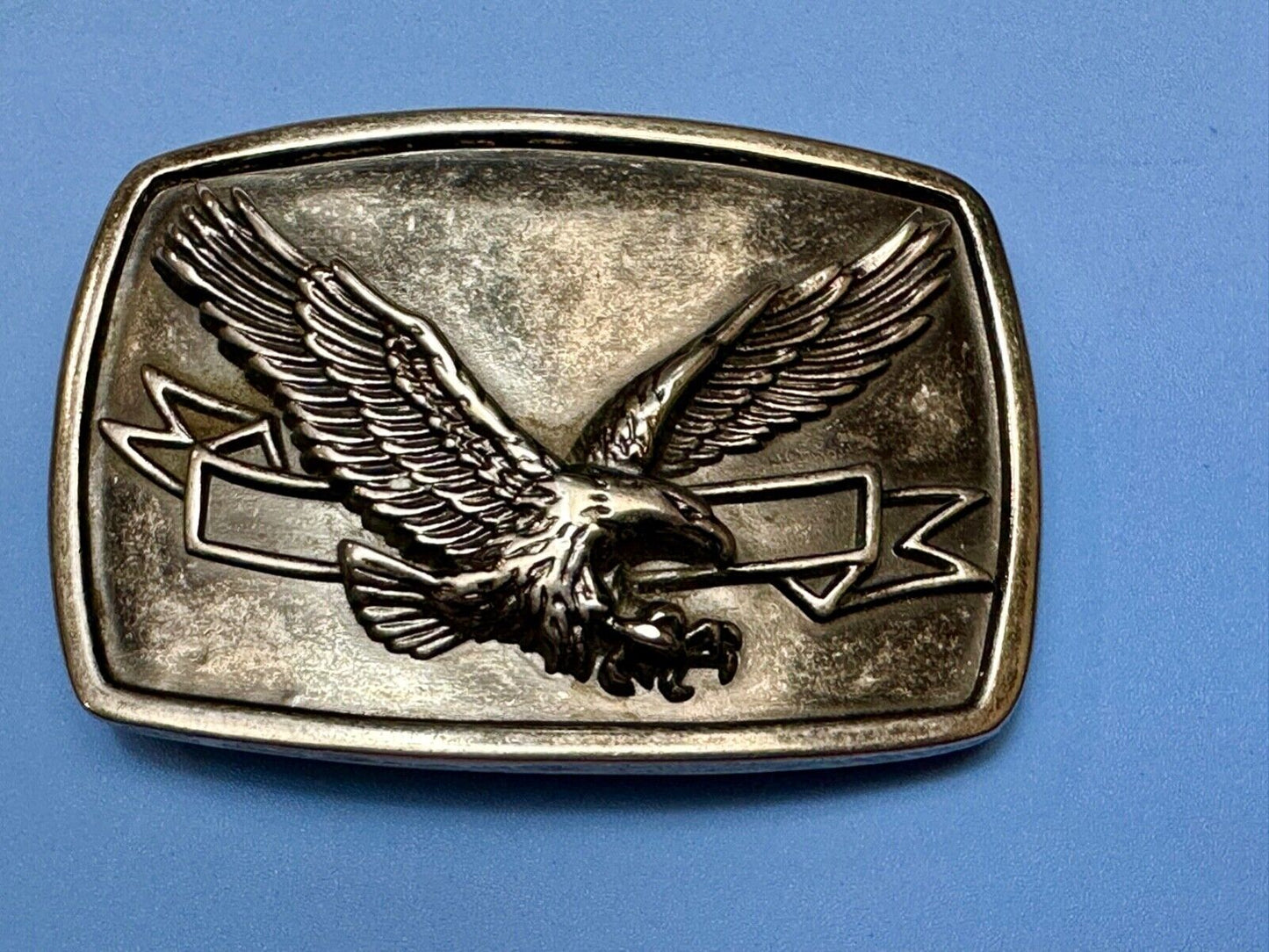 American Eagle with wings wide flying high in front of ribbon belt buckle