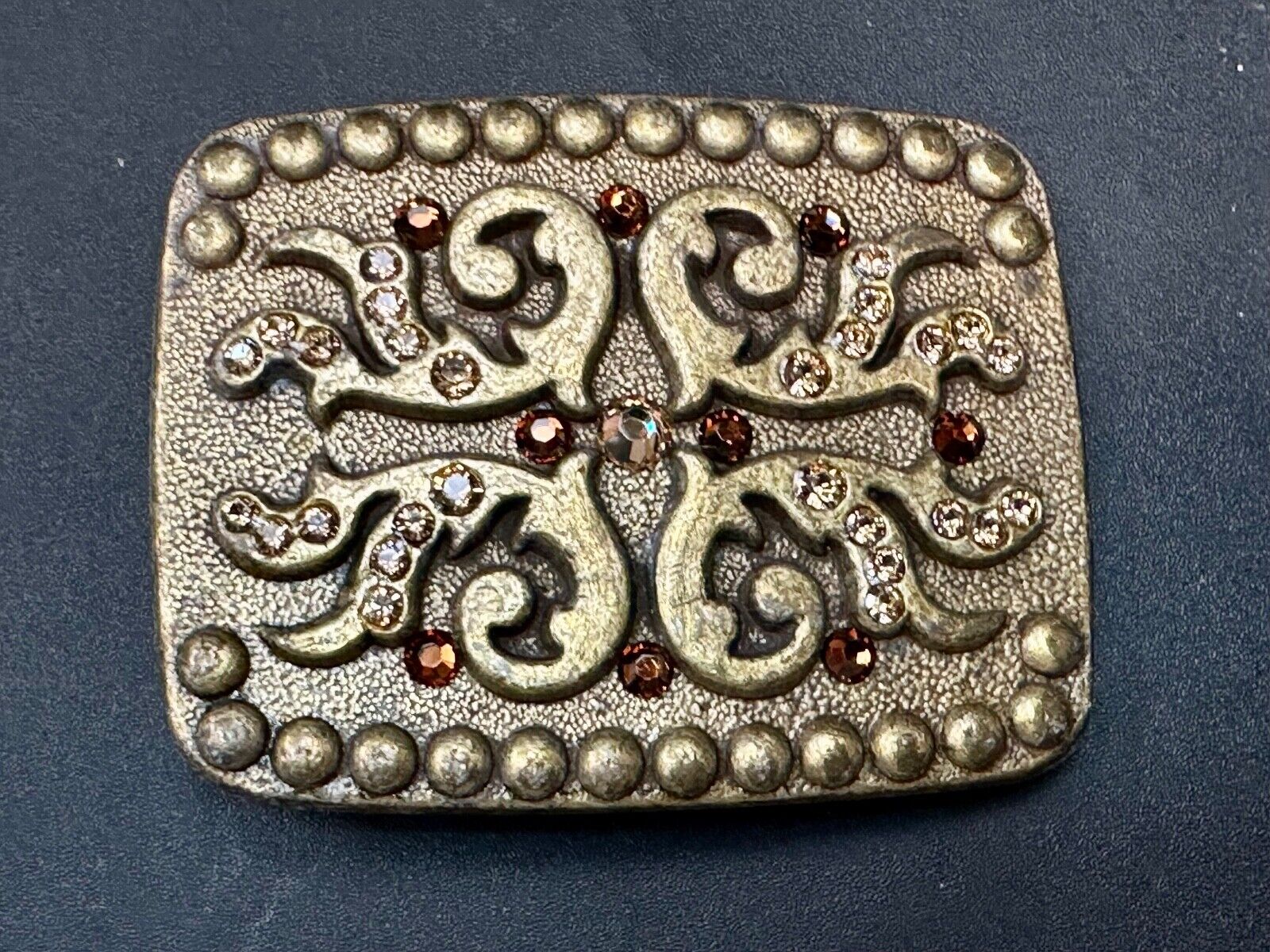 unique rhinestone accented swirl pattern on rounded rectangular belt buckle