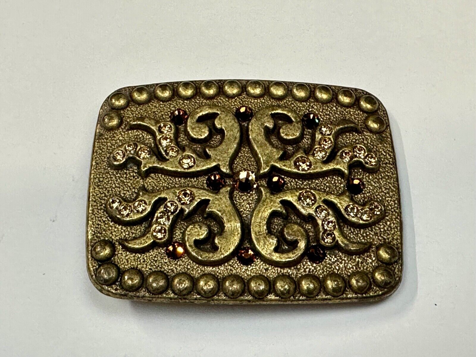 unique rhinestone accented swirl pattern on rounded rectangular belt buckle