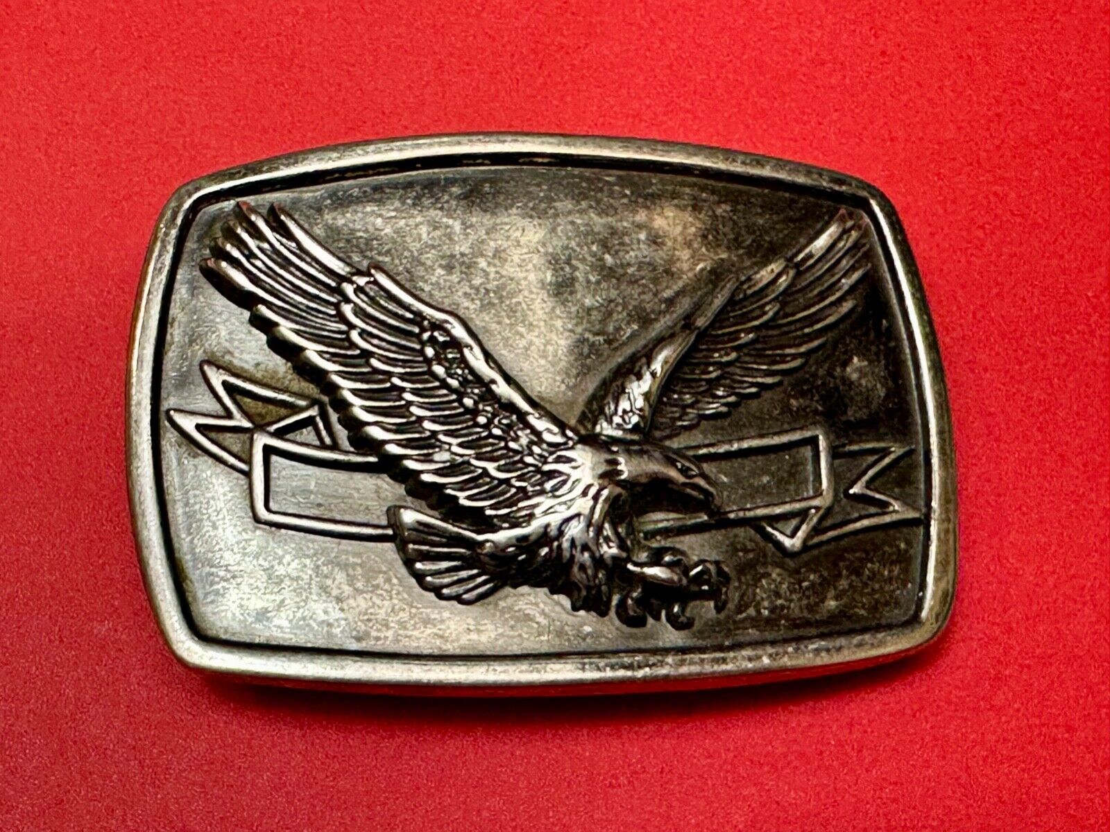American Eagle with wings wide flying high in front of ribbon belt buckle