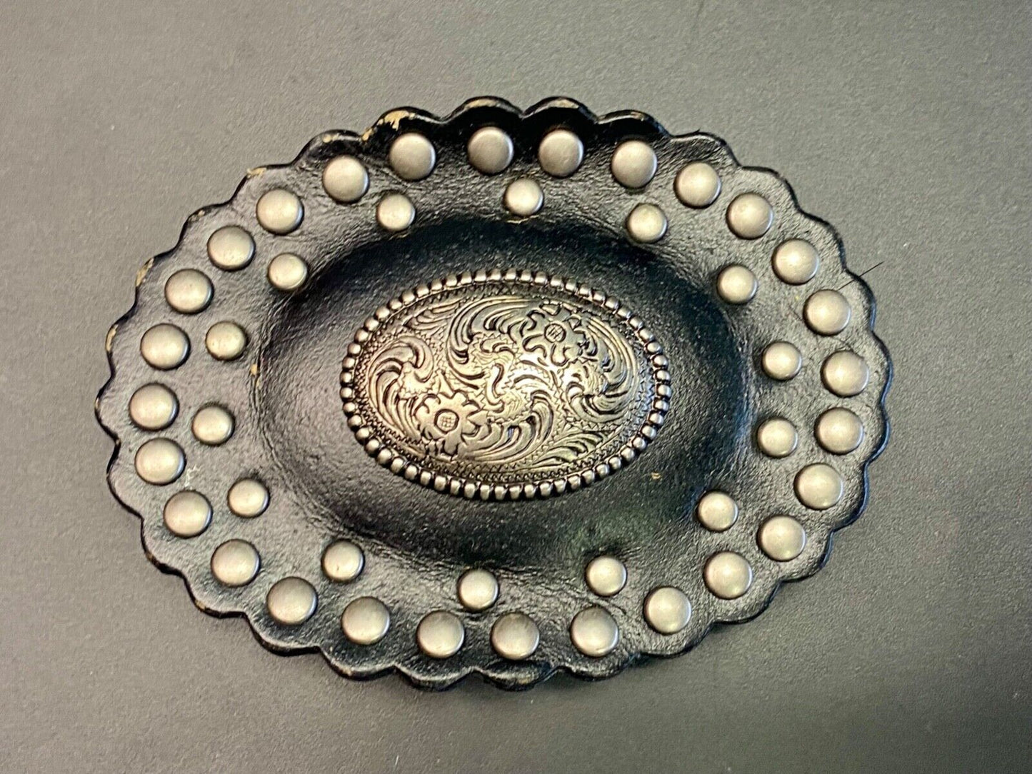 4" wide studded black leather oval belt buckle with flower swirl center