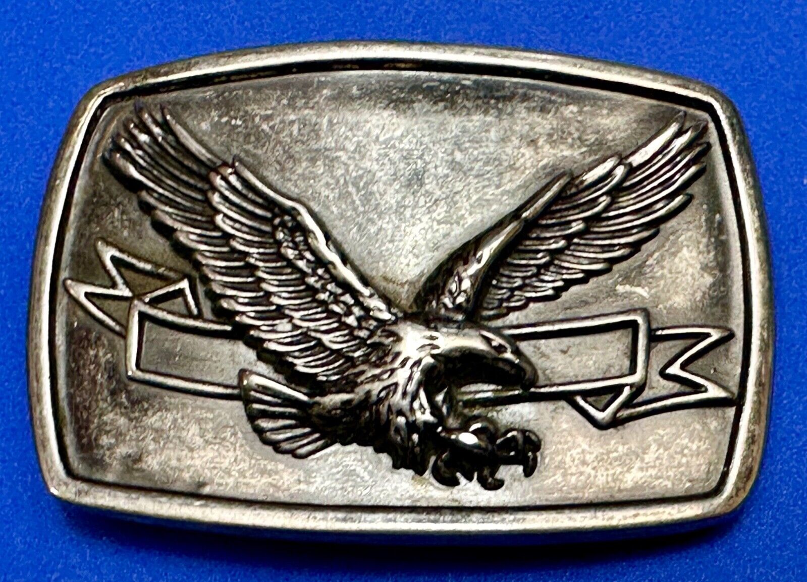 American Eagle with wings wide flying high in front of ribbon belt buckle