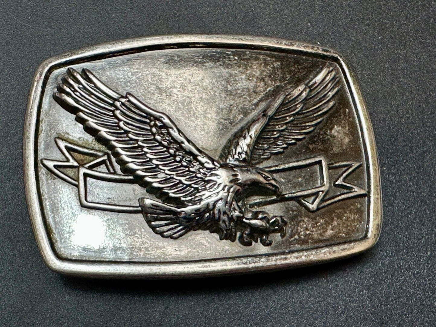 American Eagle with wings wide flying high in front of ribbon belt buckle