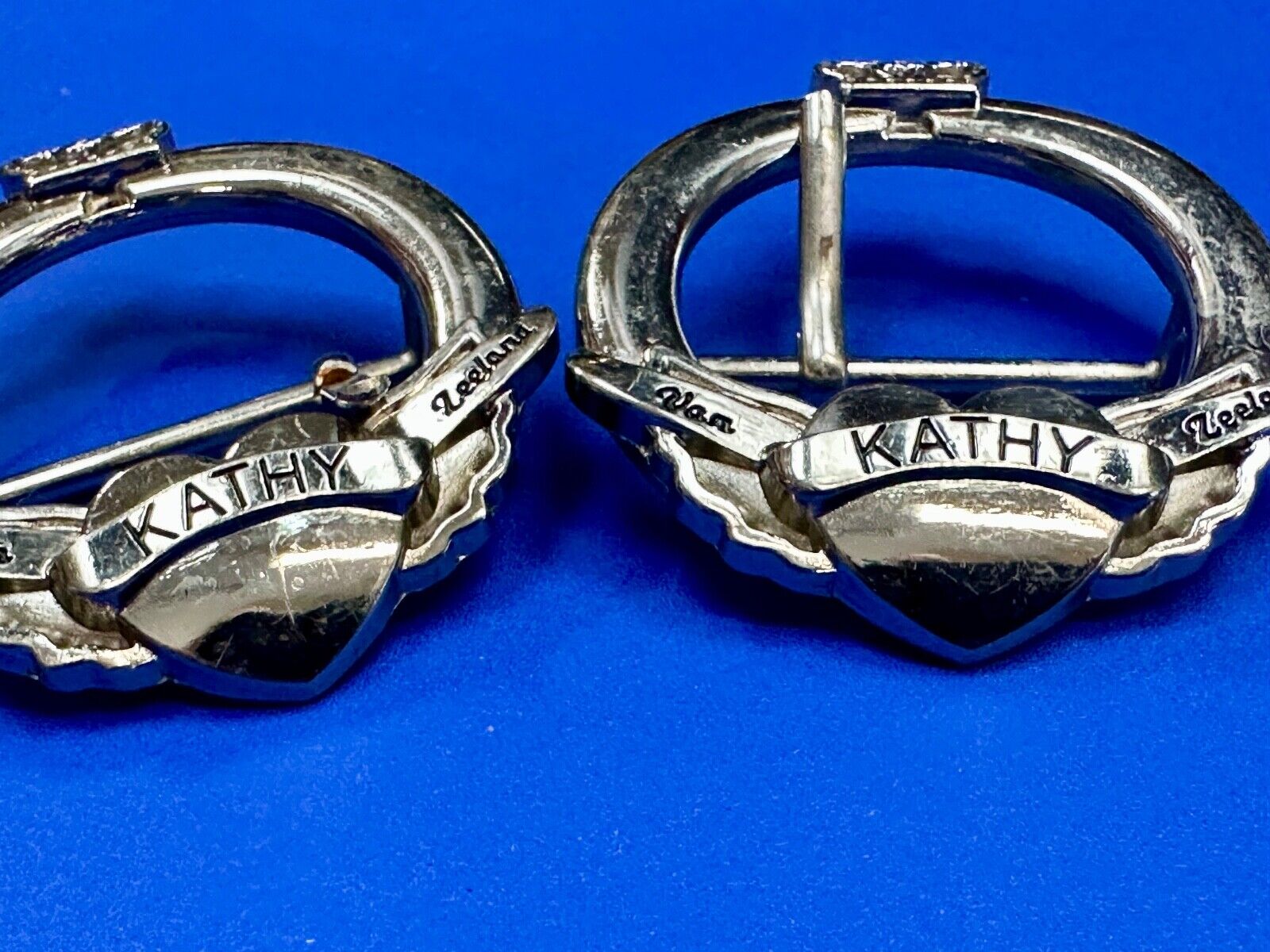 Two Kathy Van Zeeland signed silver tone round heart accented belt buckles