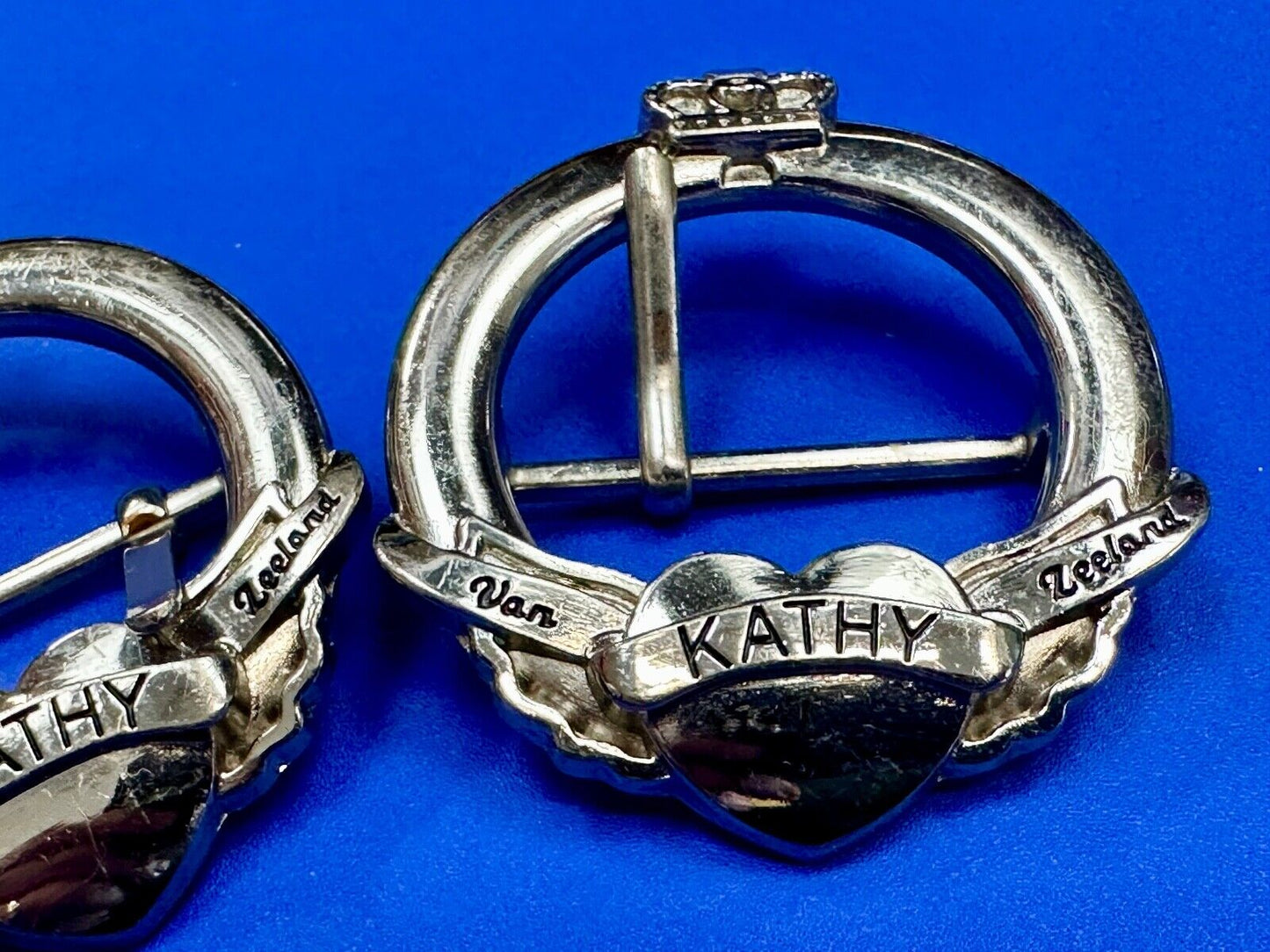 Two Kathy Van Zeeland signed silver tone round heart accented belt buckles