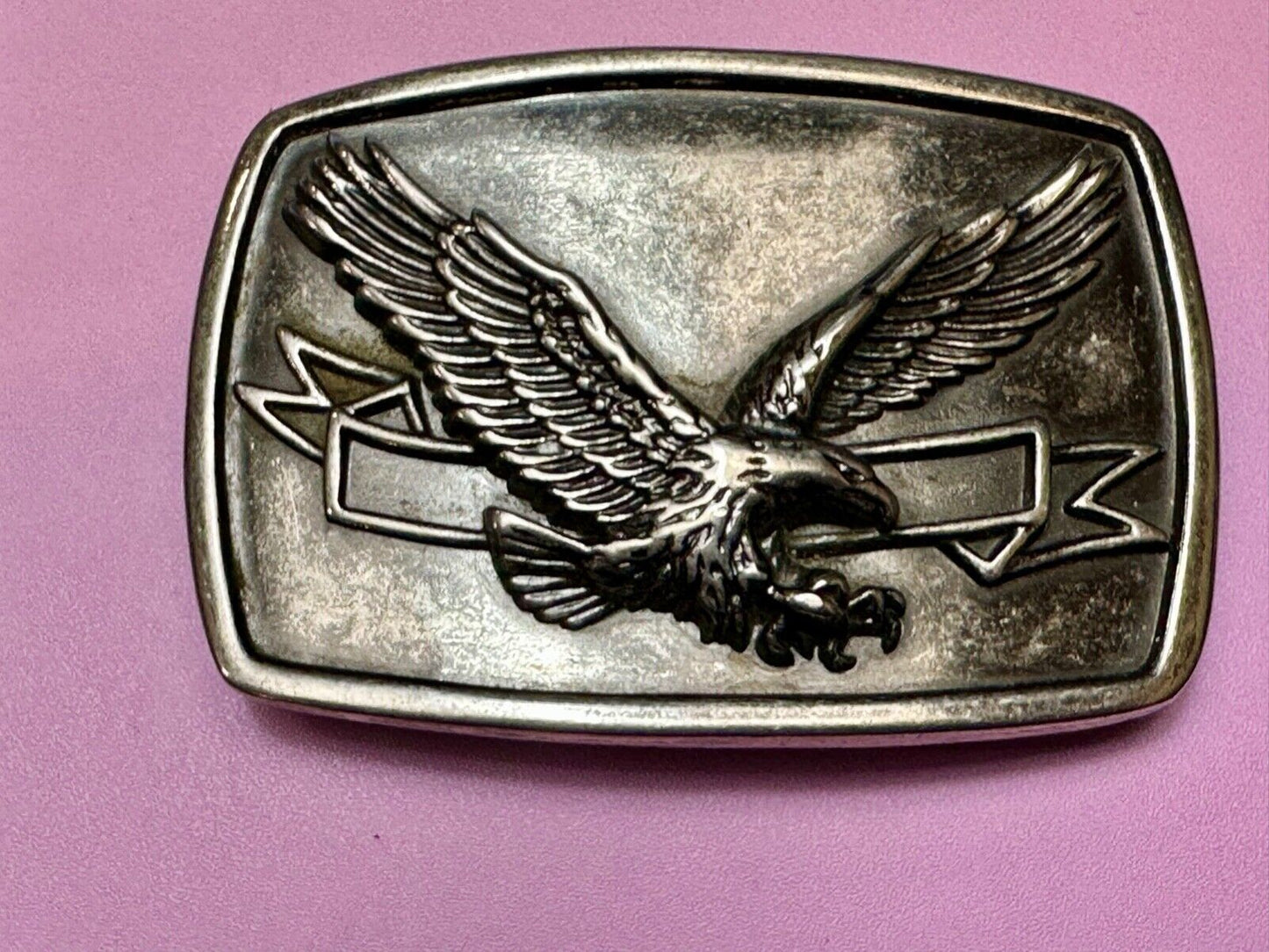 American Eagle with wings wide flying high in front of ribbon belt buckle