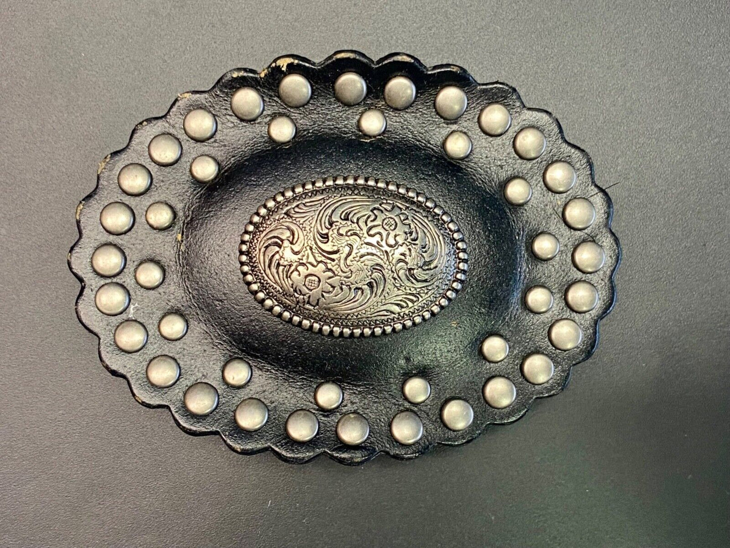 4" wide studded black leather oval belt buckle with flower swirl center