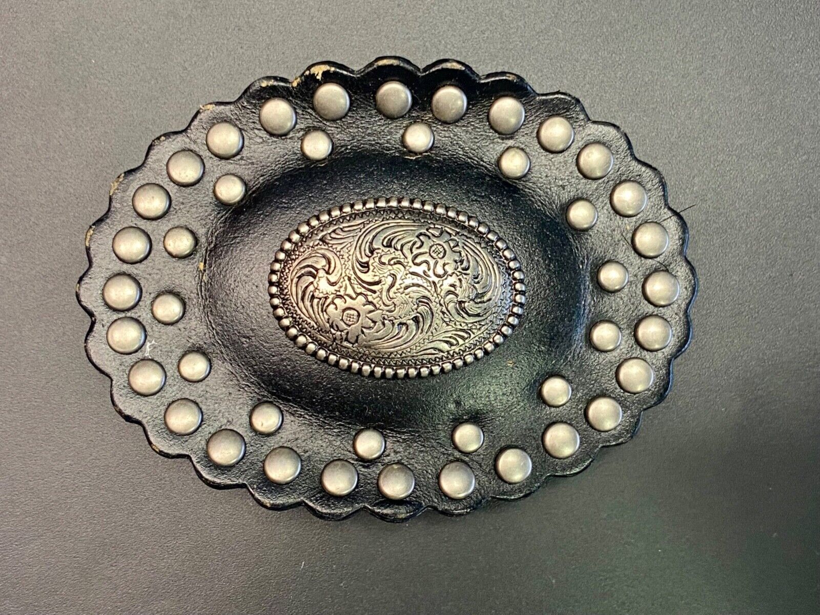 4" wide studded black leather oval belt buckle with flower swirl center