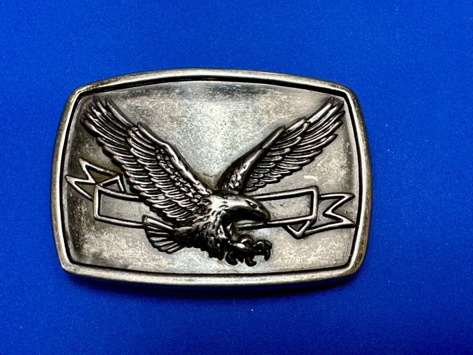 American Eagle with wings wide flying high in front of ribbon belt buckle