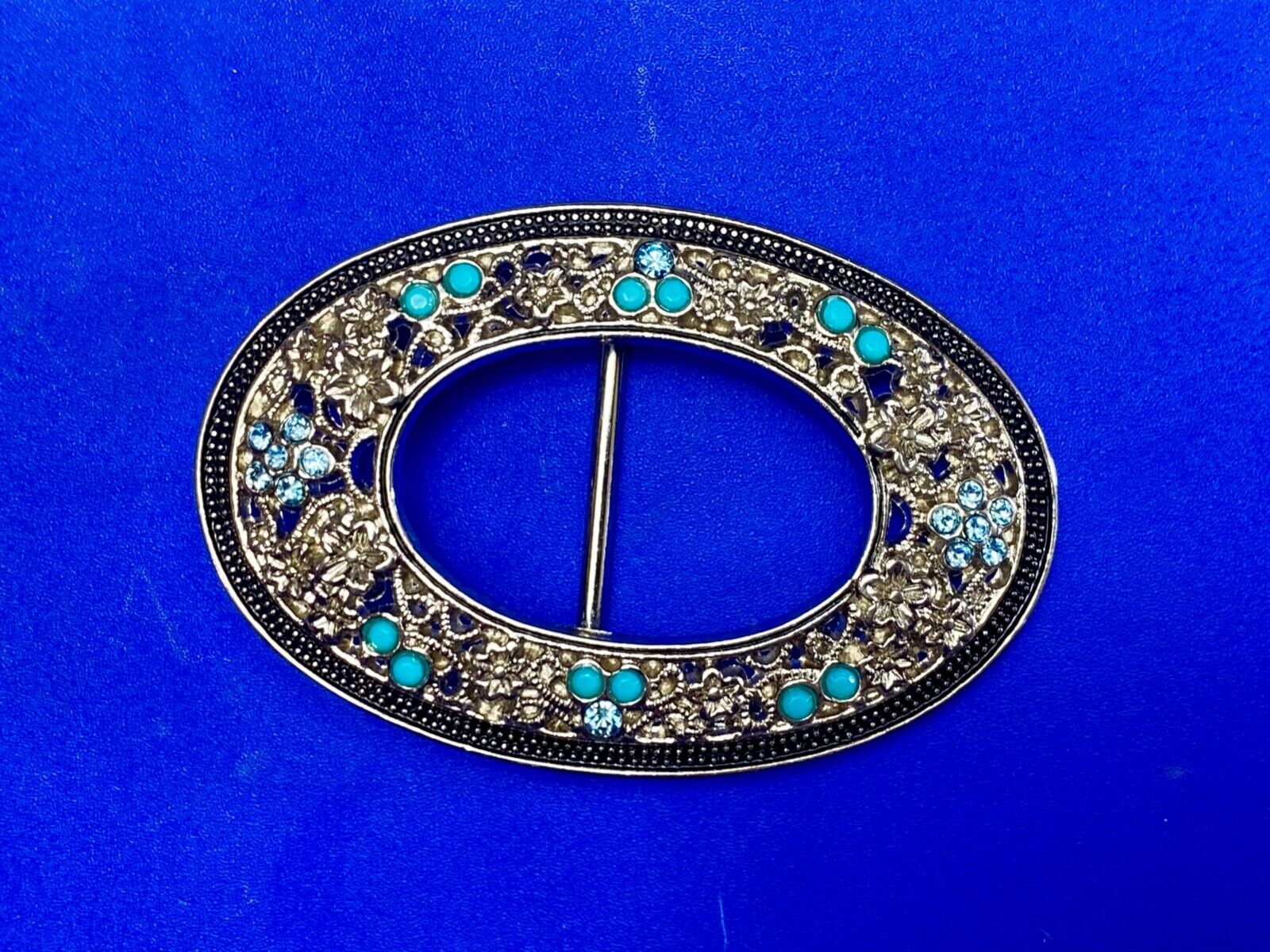 Unique blue rhinestone accented oval see though silver tone belt buckle