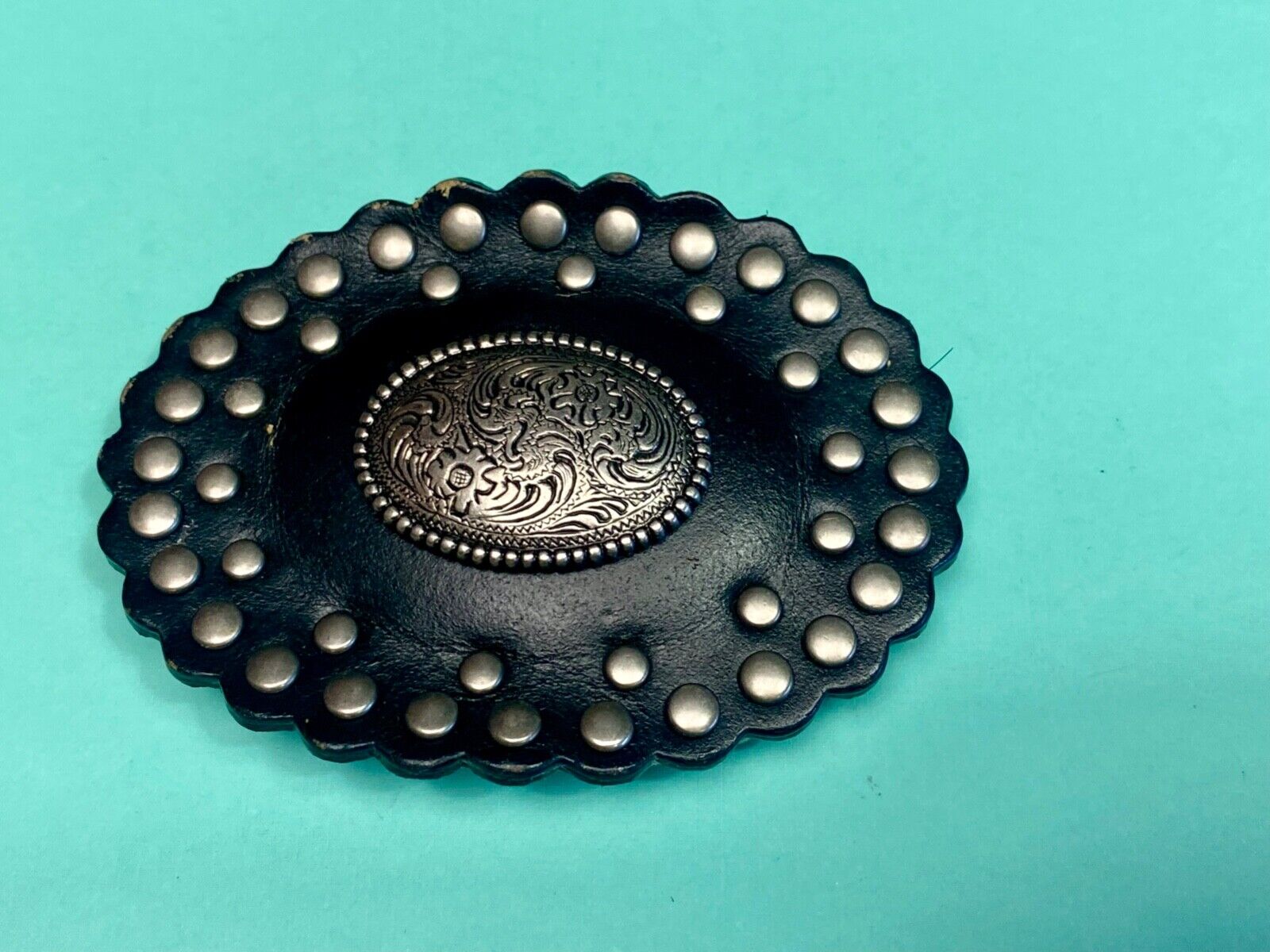 4" wide studded black leather oval belt buckle with flower swirl center
