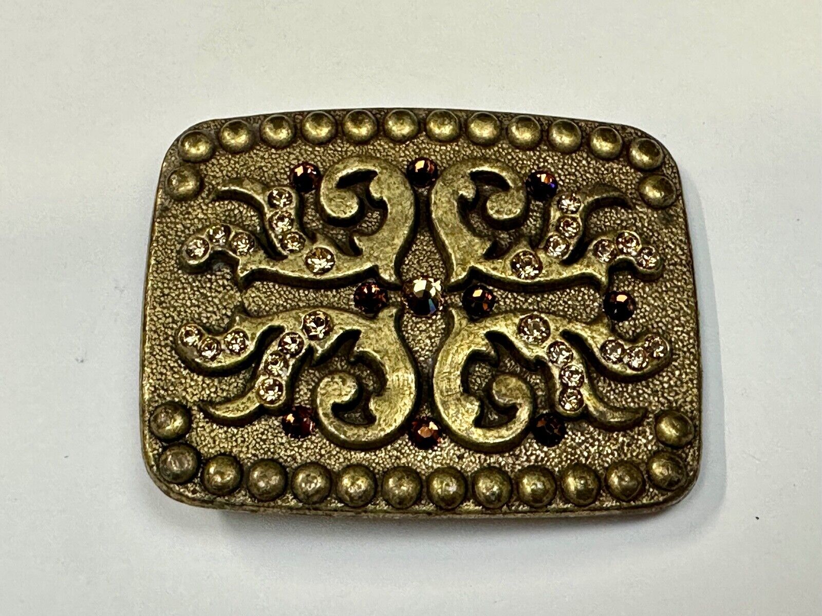 unique rhinestone accented swirl pattern on rounded rectangular belt buckle