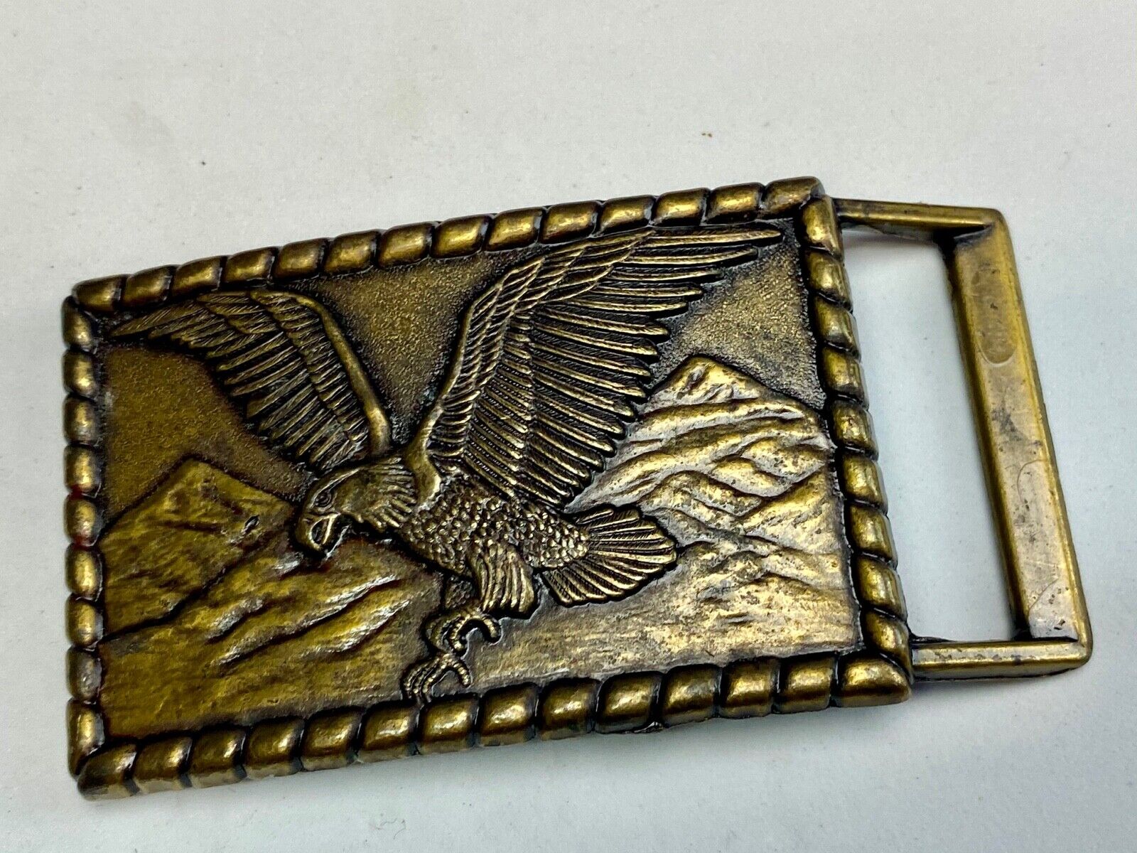 Vintage flying, hunting, fishing American eagle belt buckle with western boarder