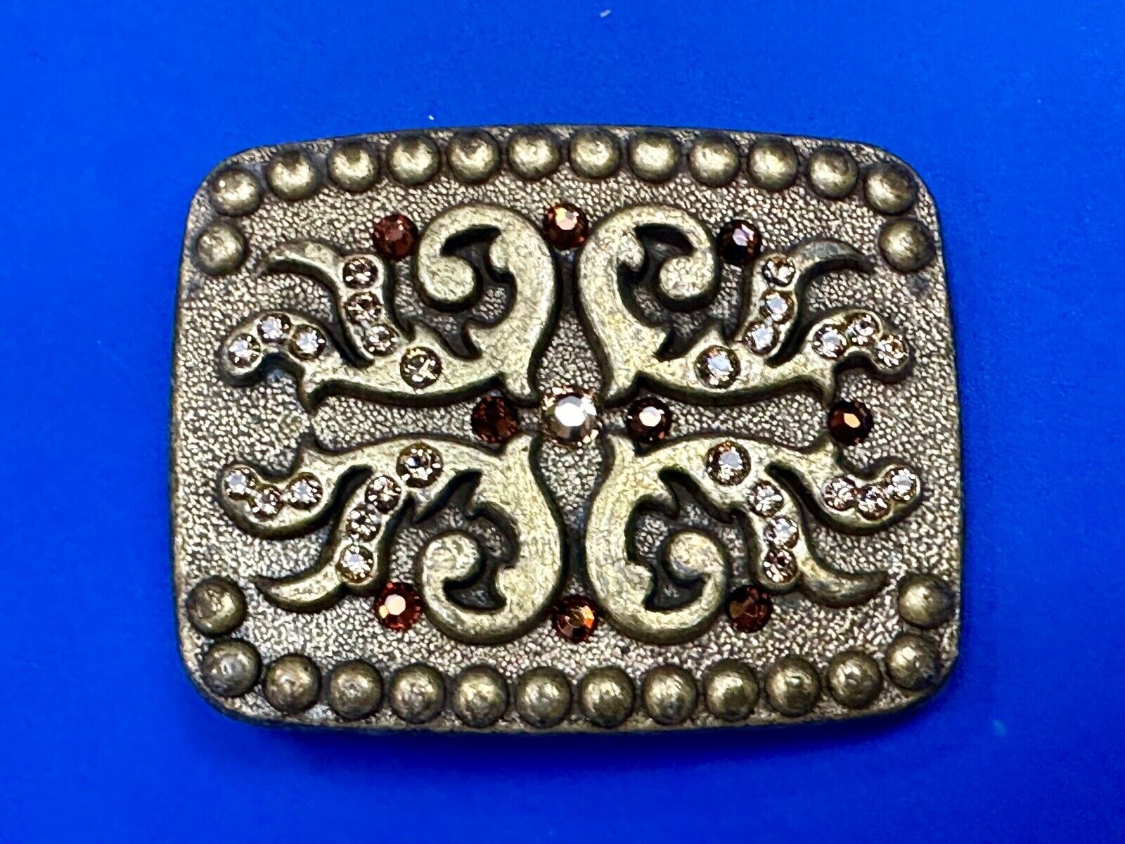 unique rhinestone accented swirl pattern on rounded rectangular belt buckle