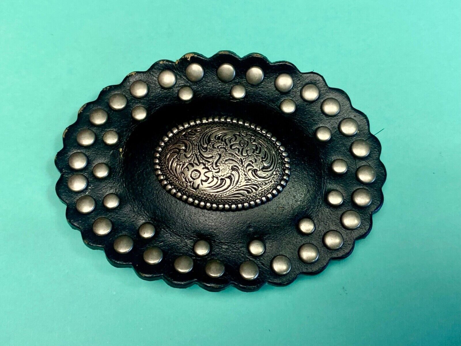 4" wide studded black leather oval belt buckle with flower swirl center