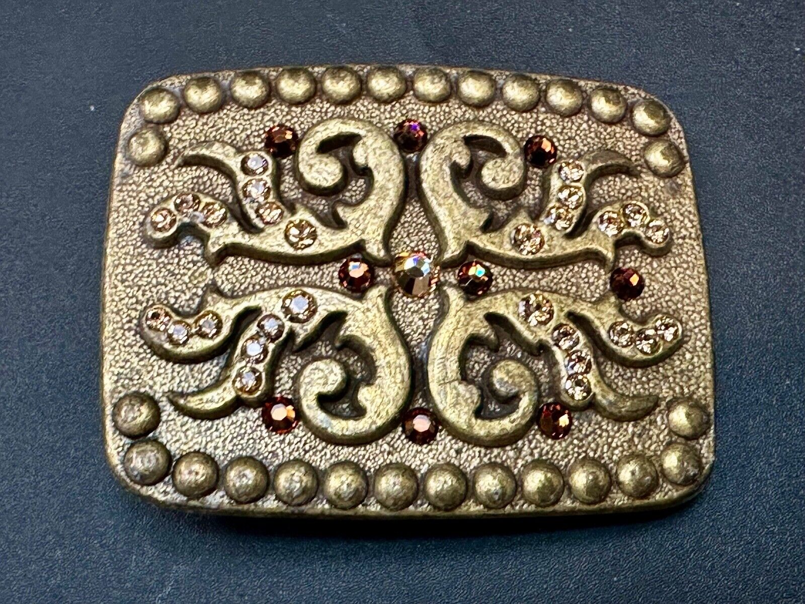 unique rhinestone accented swirl pattern on rounded rectangular belt buckle