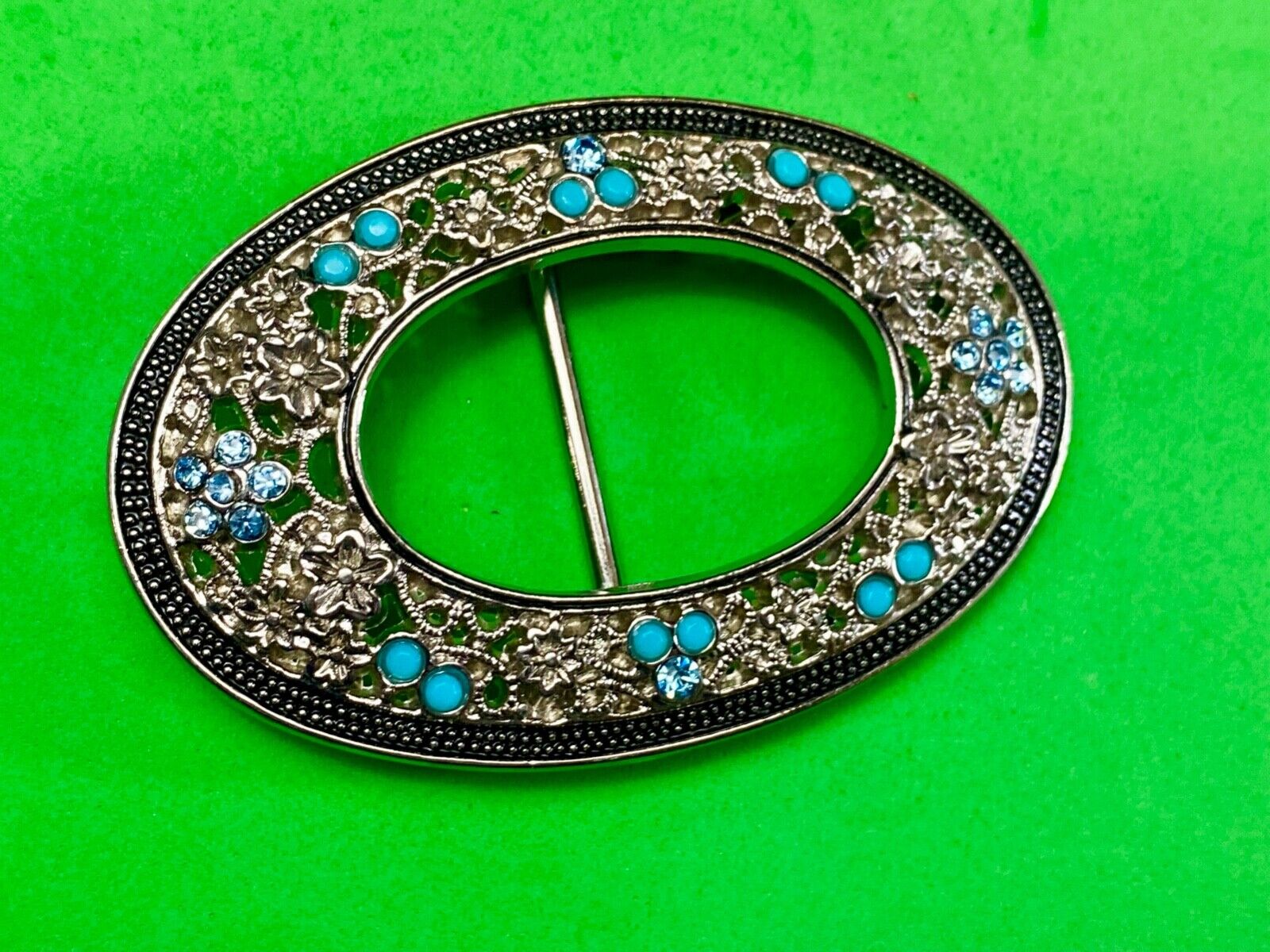 Unique blue rhinestone accented oval see though silver tone belt buckle