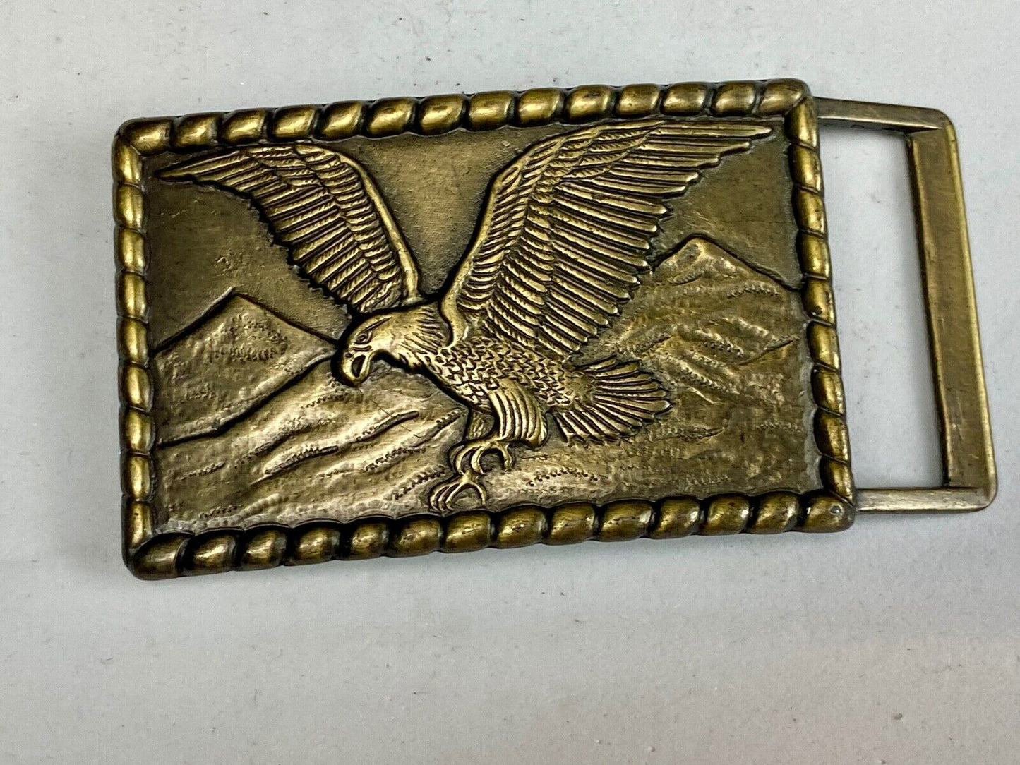 Vintage flying, hunting, fishing American eagle belt buckle with western boarder