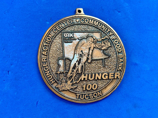 award round medal from El Tour De Tucson HUNGER Race