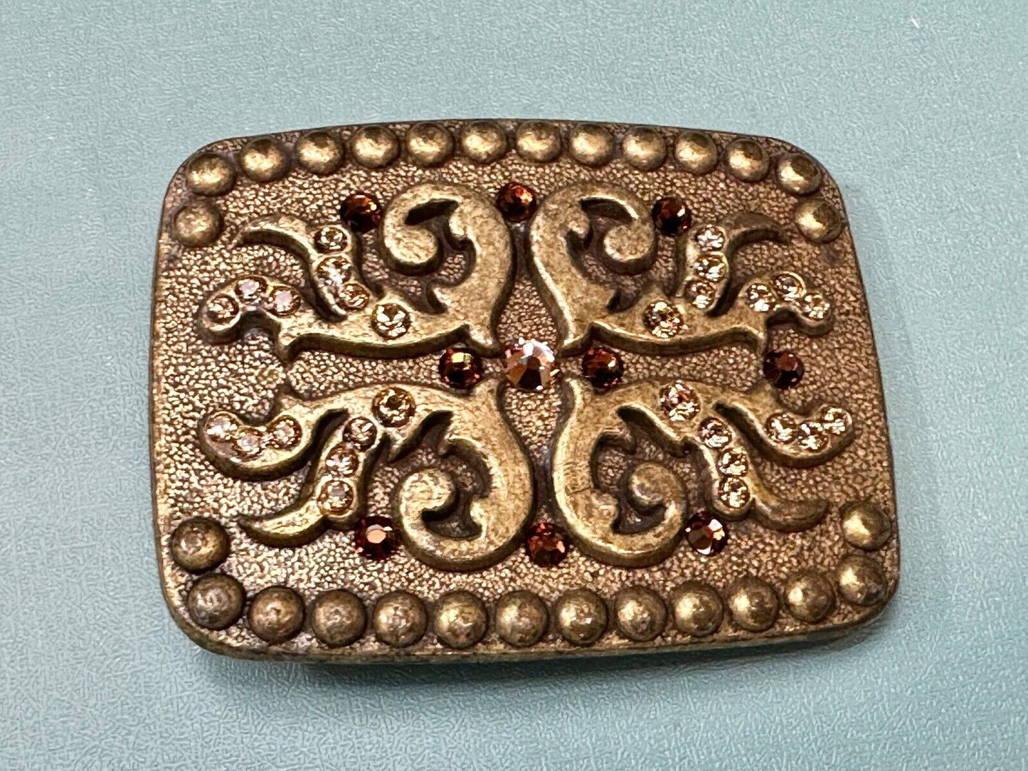 unique rhinestone accented swirl pattern on rounded rectangular belt buckle