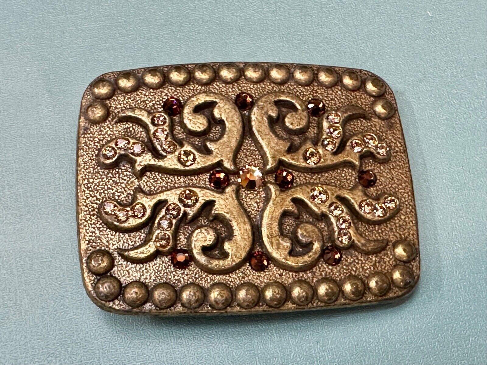 unique rhinestone accented swirl pattern on rounded rectangular belt buckle