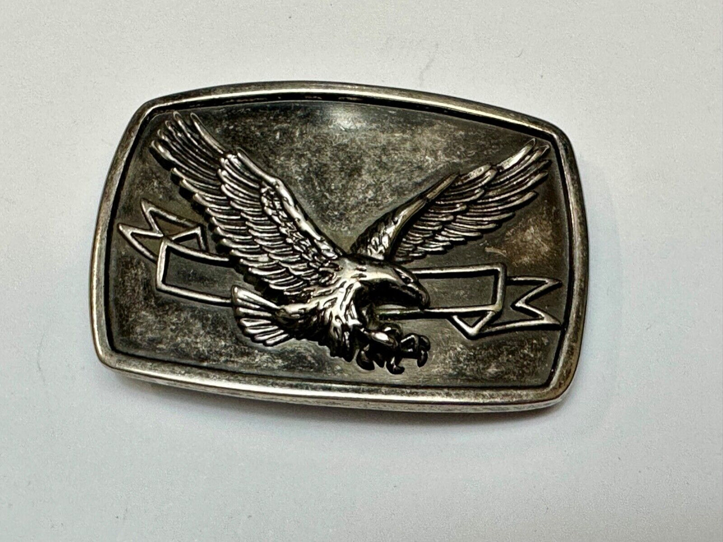 American Eagle with wings wide flying high in front of ribbon belt buckle