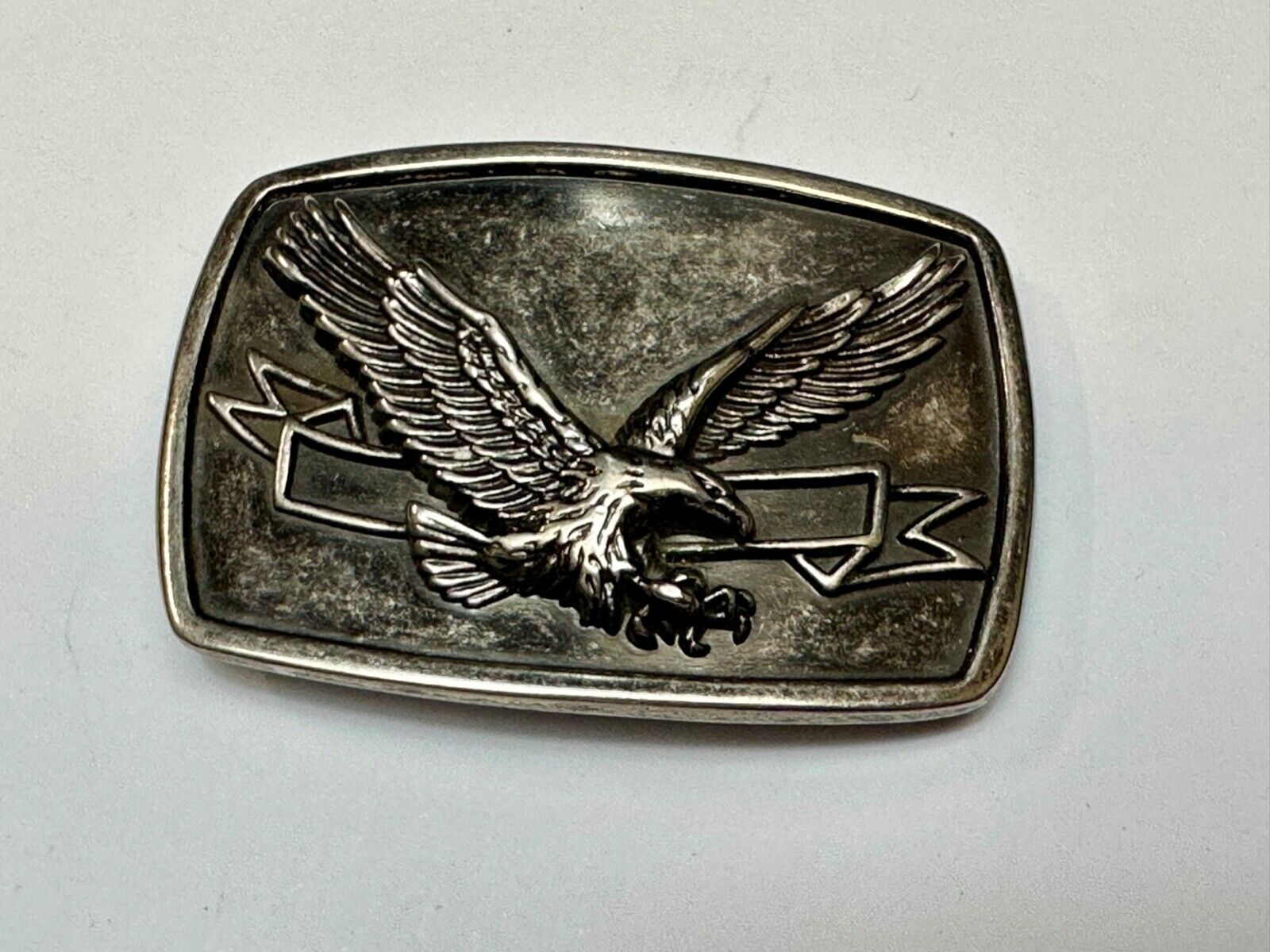 American Eagle with wings wide flying high in front of ribbon belt buckle