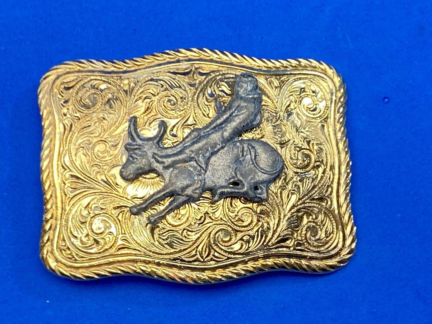bull riding rodeo cowboy on beautiful gold color flower swirl belt buckle 